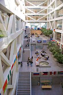 Large open building with granite steps running up the left side of the multi-storey building and modern fountains centered on each floor